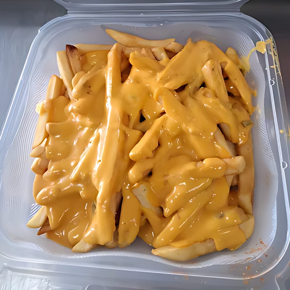 Fast Eddie's cheesy fries, a clear plastic container filled with golden fries smothered in melted cheese.