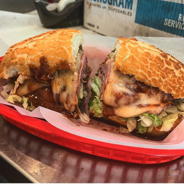 A Fast Eddie's Sandwich Shop sandwich, cut in half, with melted cheese, meat, and lettuce.