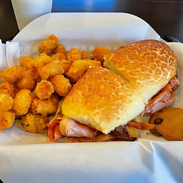 A Fast Eddie's sandwich with ham, cheese, and sauce, served with tater tots and a cookie.