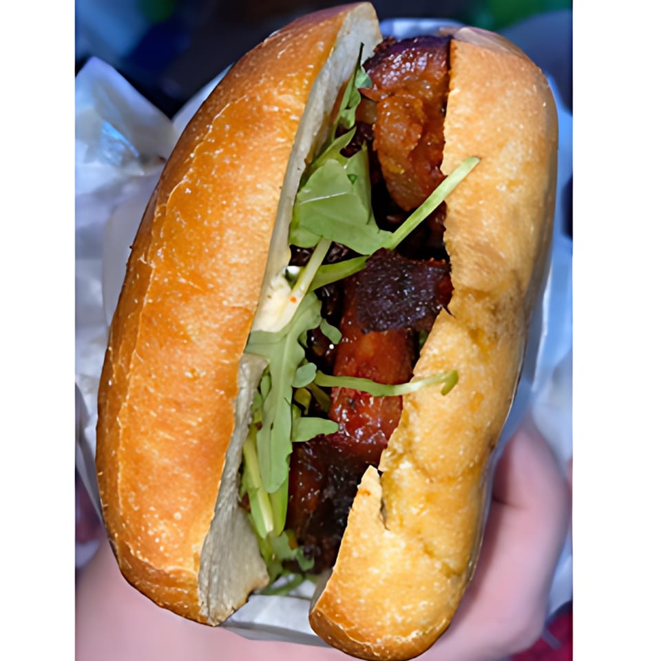 Close-up of a Fast Eddie's sandwich with dark meat, green arugula, and a golden-brown bun.