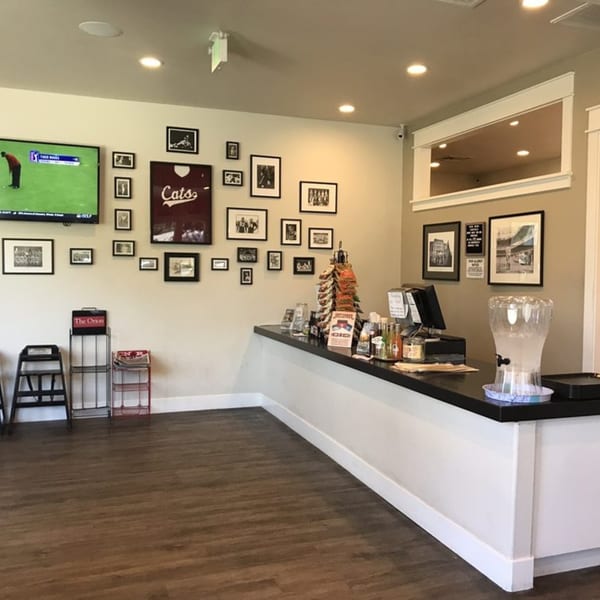 Interior of Fast Eddie's Sandwich Shop with a counter, TV, and framed pictures on the wall.