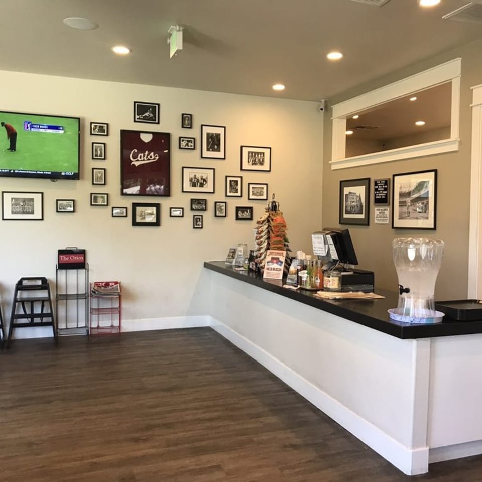 Interior of Fast Eddie's Sandwich Shop with a counter, TV, and framed pictures on the wall.